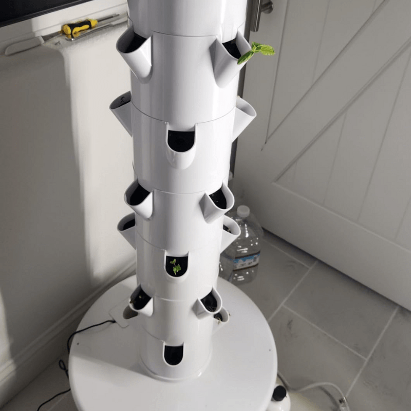 A vibrant image showcasing various vegetables thriving in a vertical hydroponic tower system, highlighting sustainable and space-saving gardening.